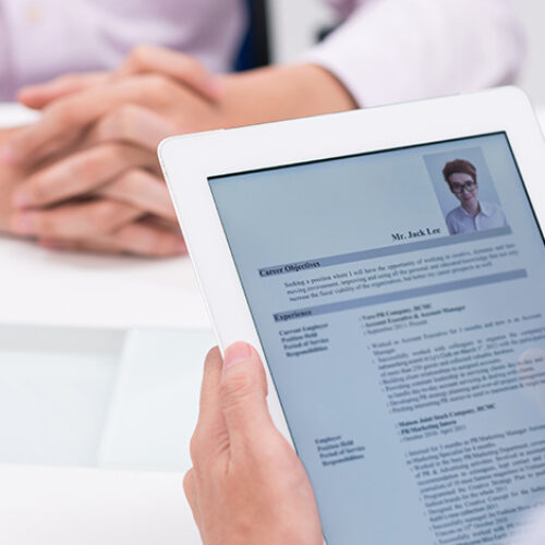 Une personne tient une tablette numérique avec un CV
